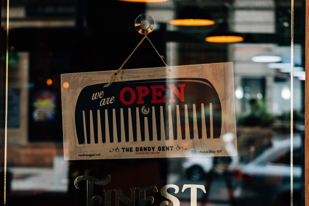 A "we are open" sign hanging on the door in front of the Derby location of The Dandy Gent