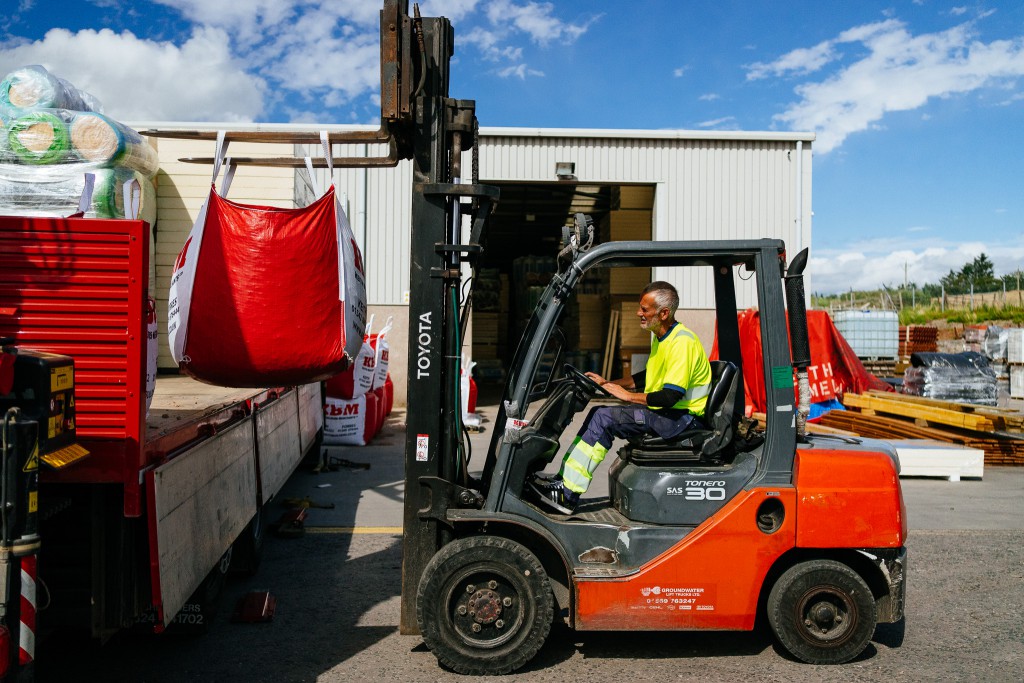 a Keith Builders Merchant forklift loads a bag of materials onto a flatbed at their warehouse in Aberdeen