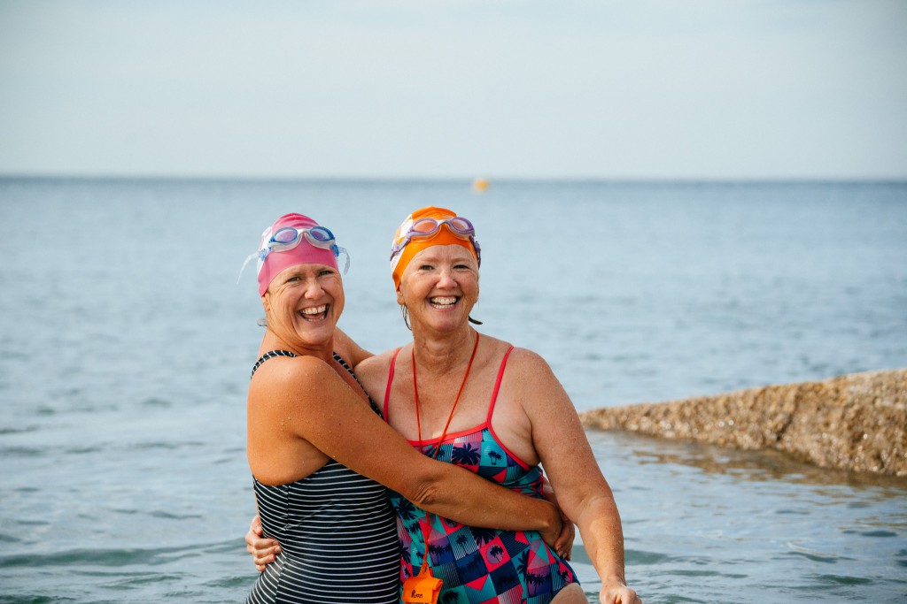 Kath and Cath of Seabirds LTD smile and hug while sea swimming