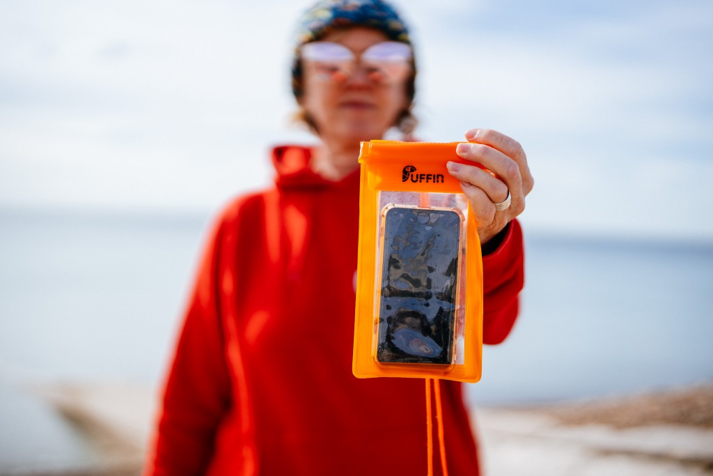 Cath holds up a Puffin branded dry bag for keeping your phone dry while you swim. These are sold by Seabirds LTD