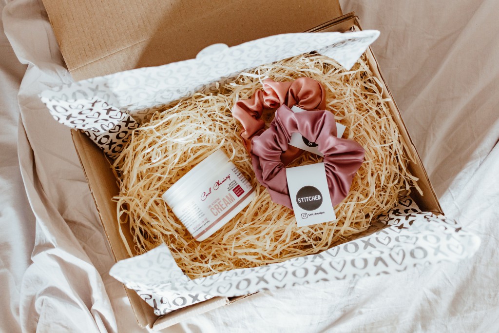 a cardboard box sits on a bed sheet showing beauty items for selling subscription boxes online